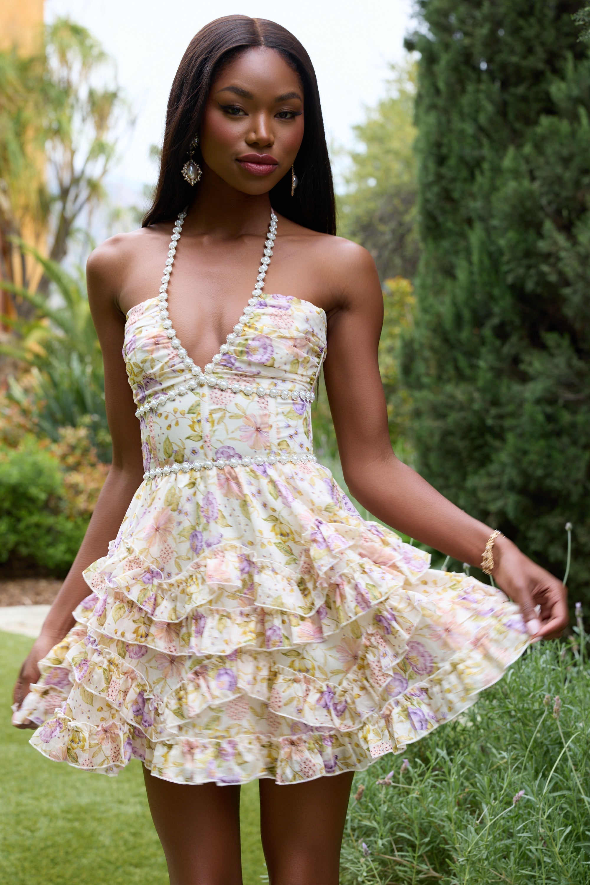 Close-up of cream floral halter mini dress showing pearl-trim plunge neckline and ruched bust detail