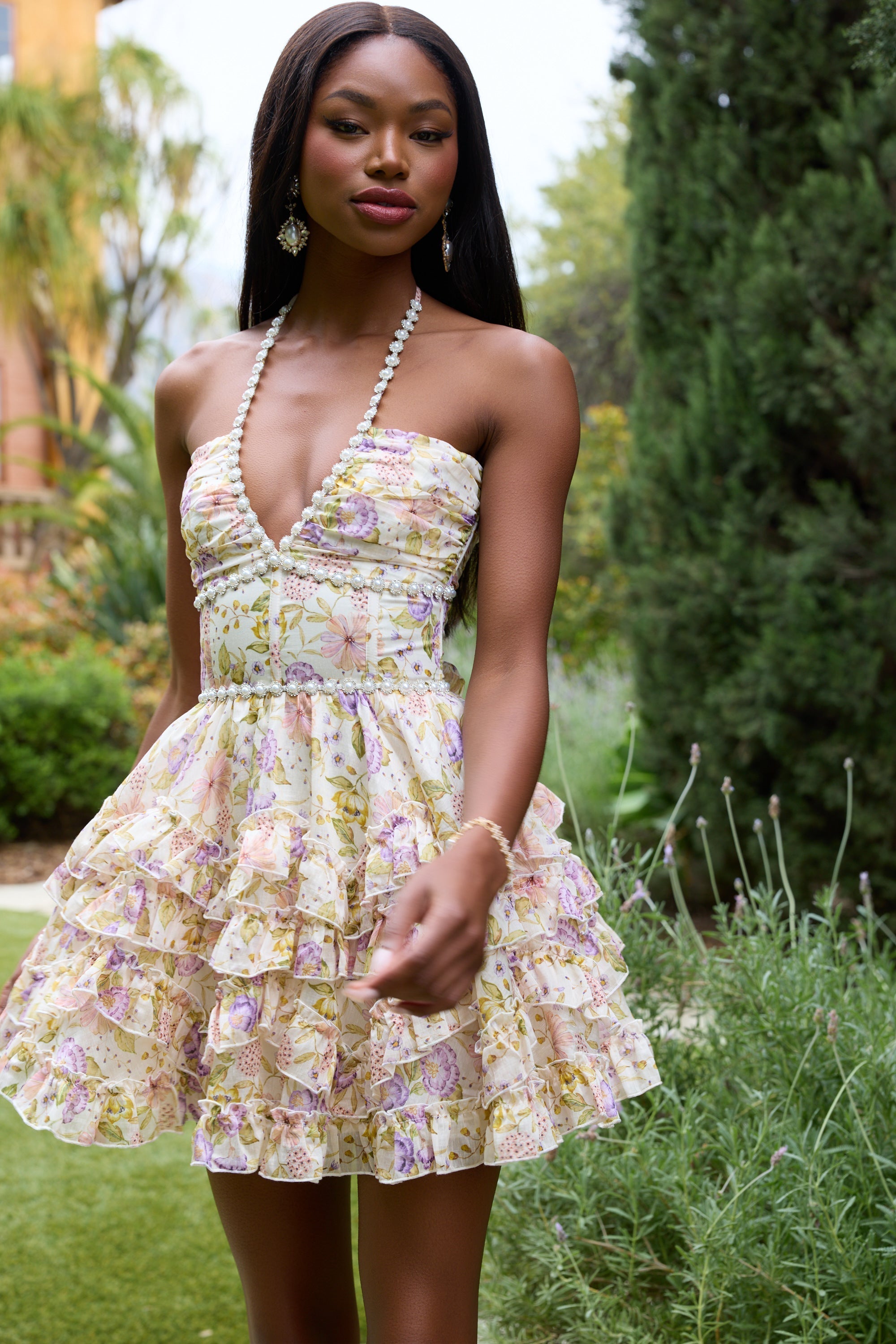 Front view cream floral halter mini dress with fitted waist, pearl trim, and layered ruffle skirt
