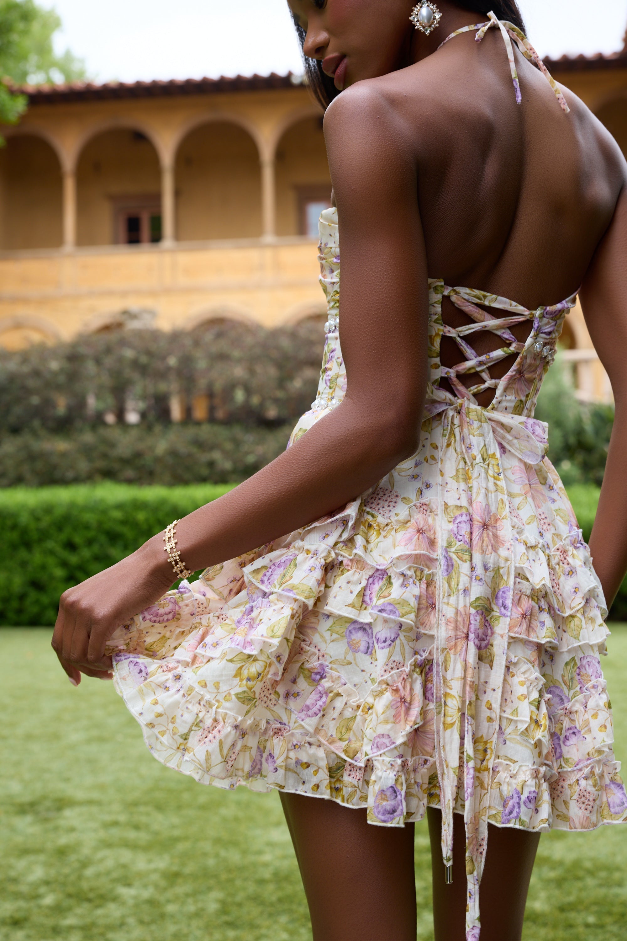 Back close-up of cream floral halter mini dress with lace-up corset back and tiered ruffle skirt