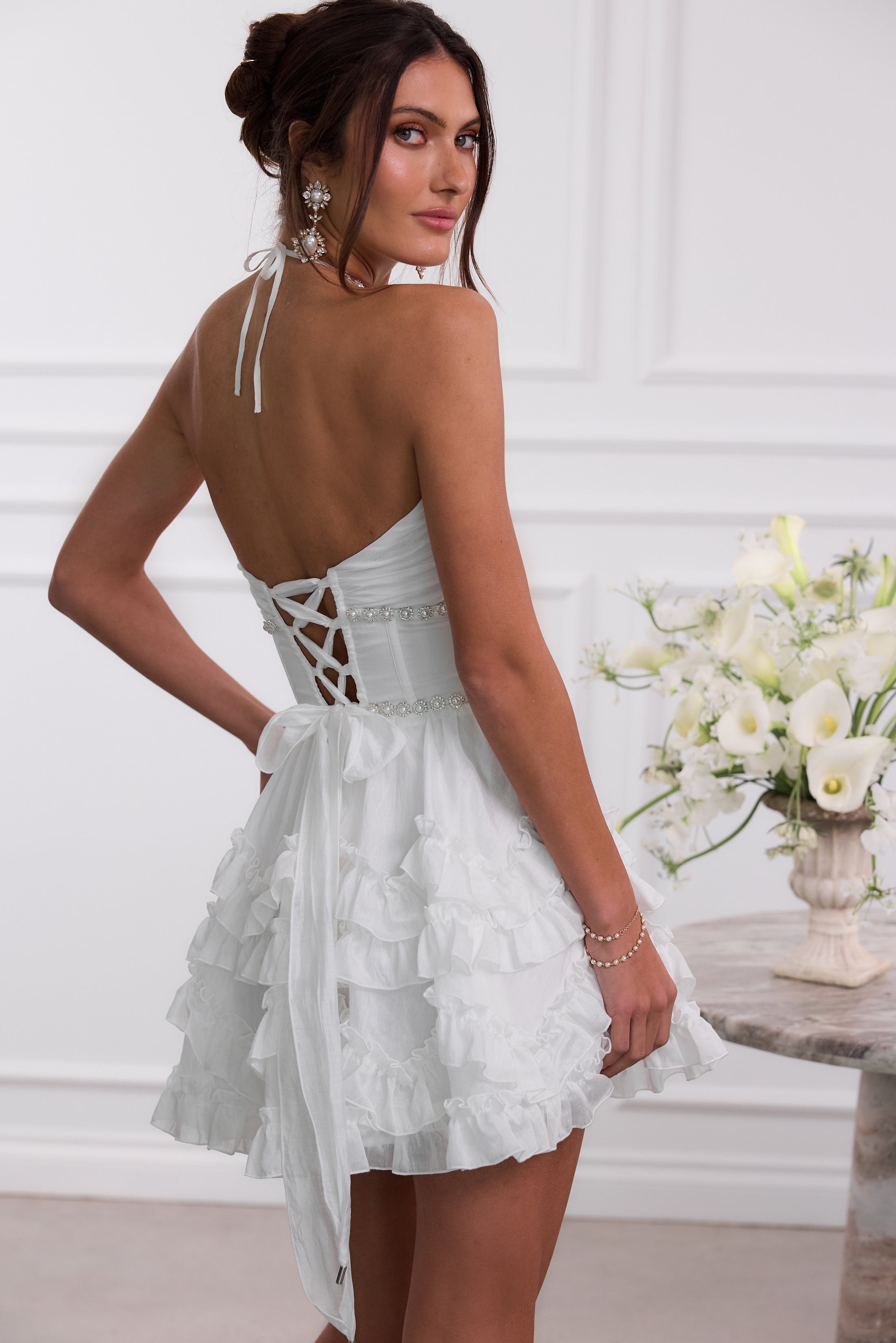 Back view white halter mini dress with lace-up corset detail and ruffled skirt, wedding guest dress