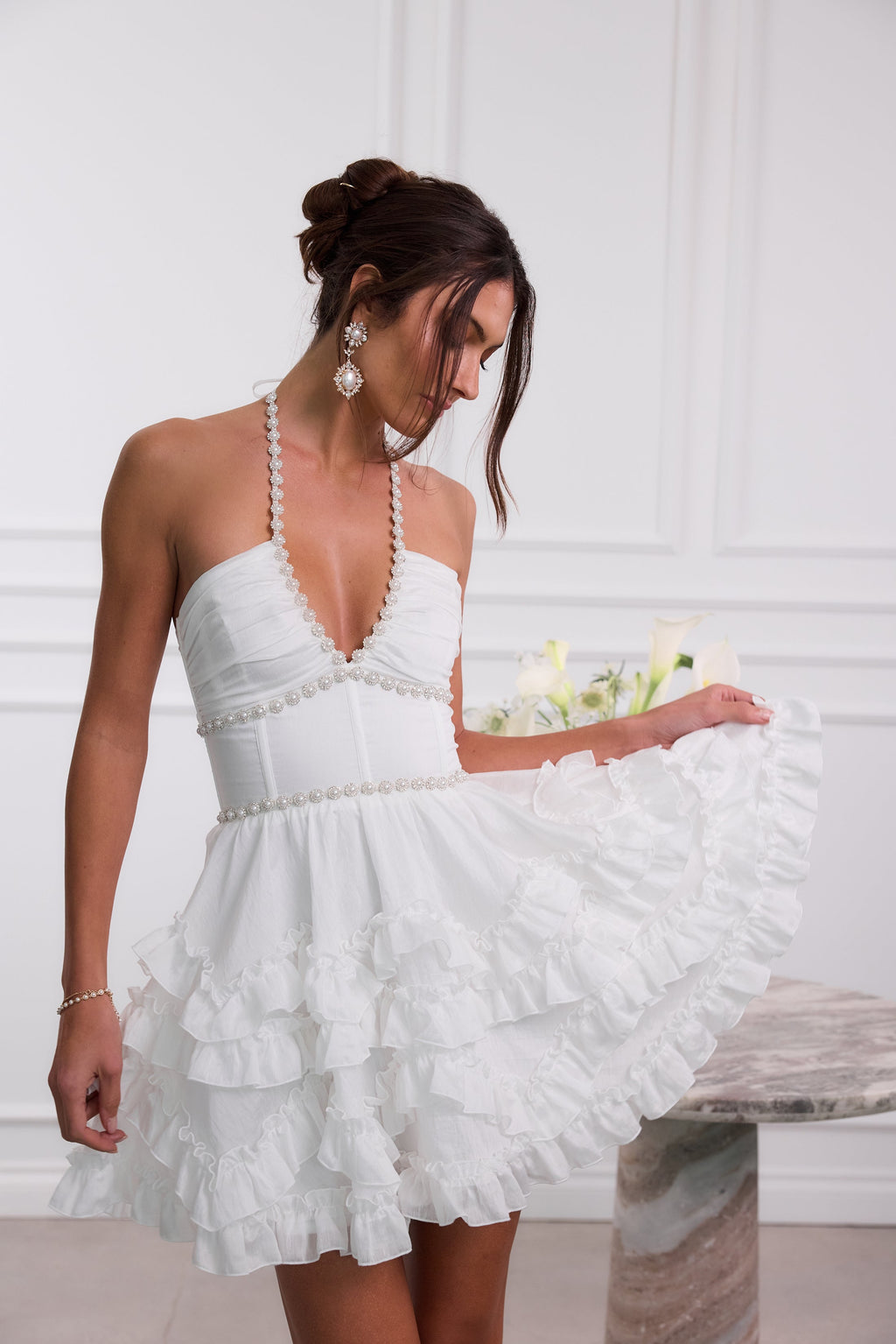 Close view white halter mini dress pearl-trim V-neck bodice and layered ruffle skirt, wedding guest dress