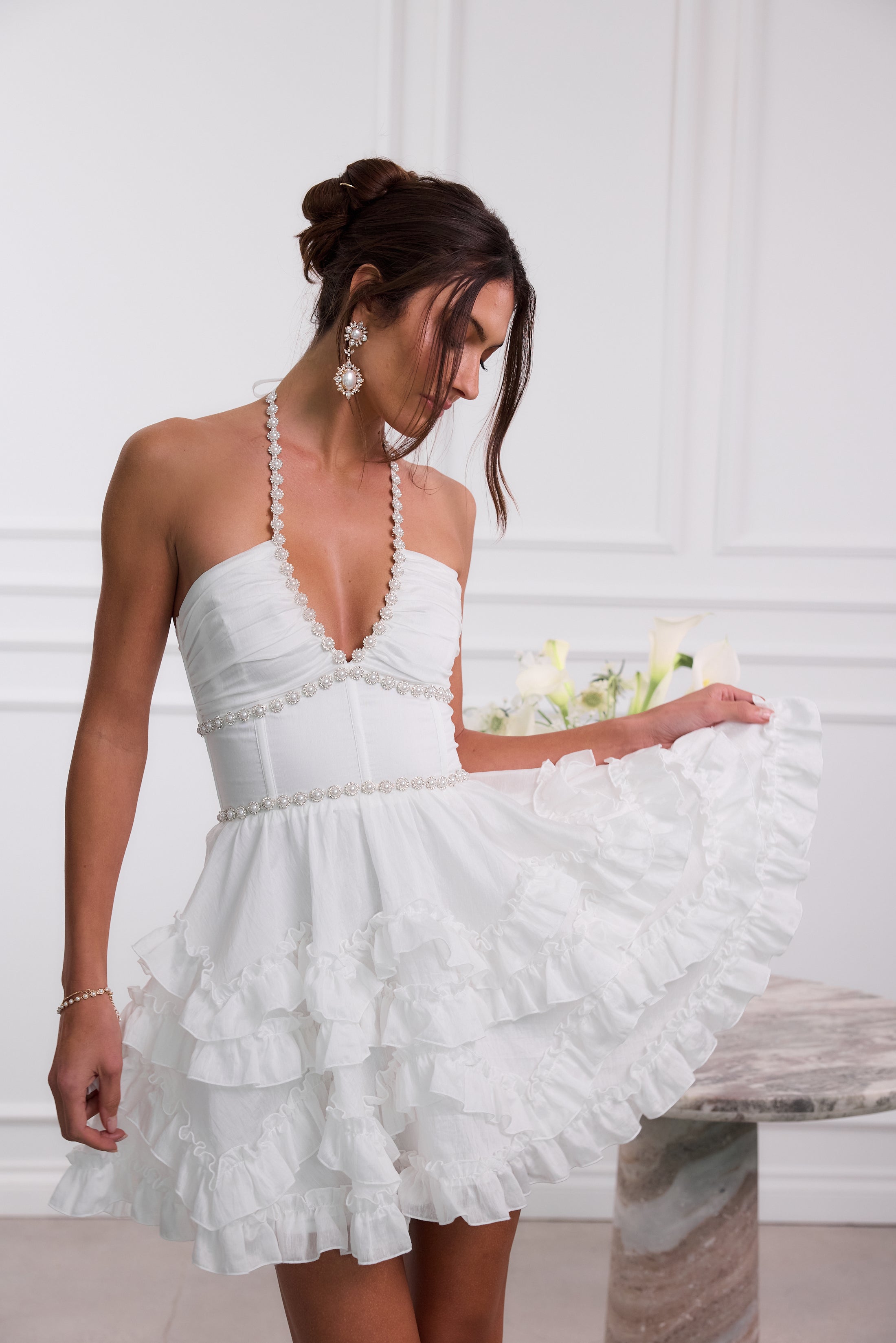 Close view white halter mini dress pearl-trim V-neck bodice and layered ruffle skirt, wedding guest dress