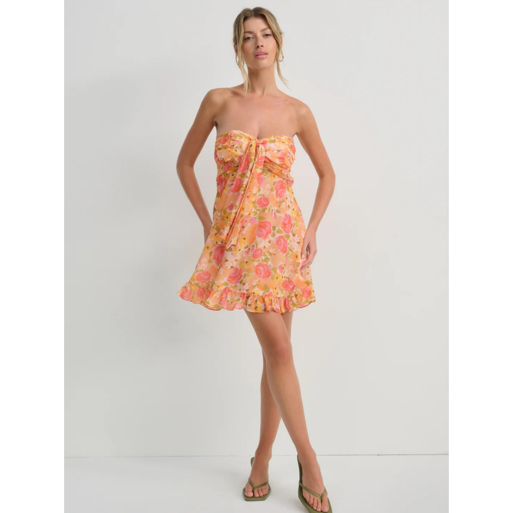 Model wearing orange floral strapless mini dress with ruffled hem and wedding guest style