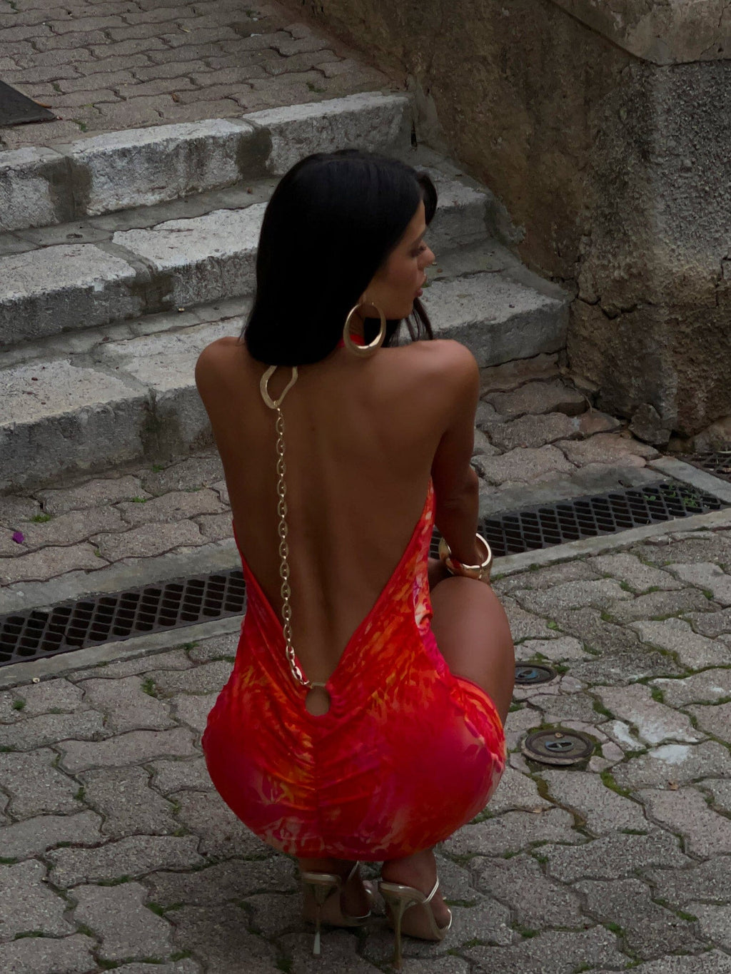 Close back detail of wedding guest halter mini dress with open back, chain strap and ring