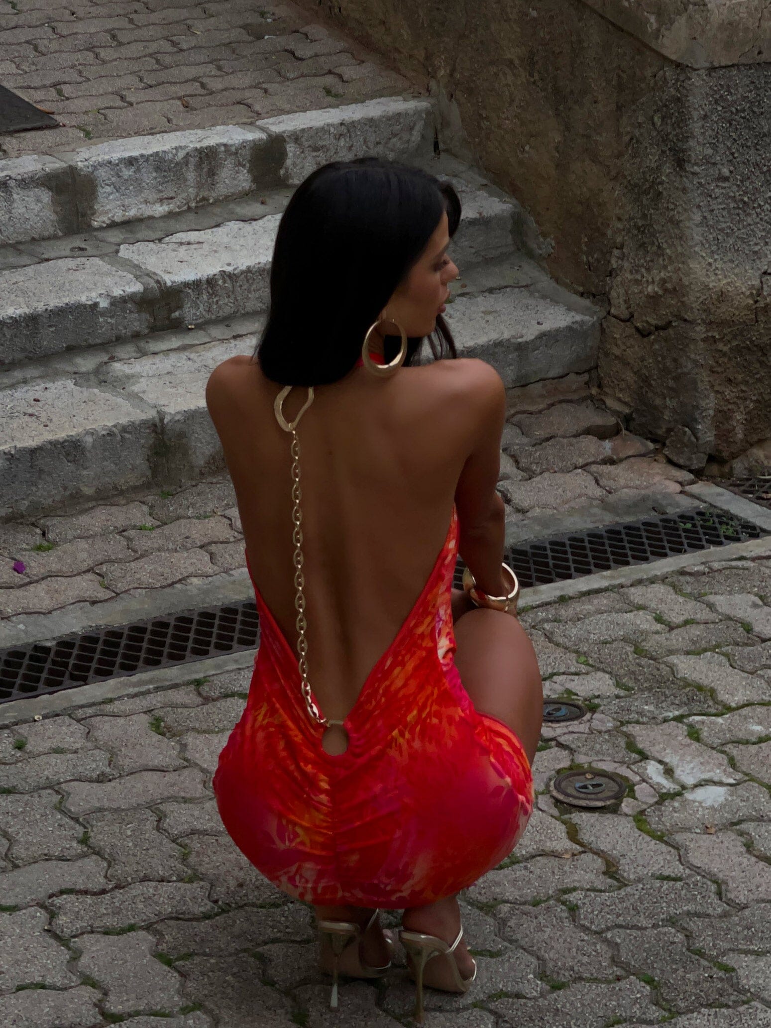 Close back detail of wedding guest halter mini dress with open back, chain strap and ring