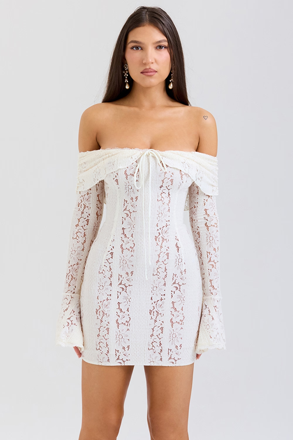 Front view of white off shoulder lace mini dress with sheer sleeves and tie neckline