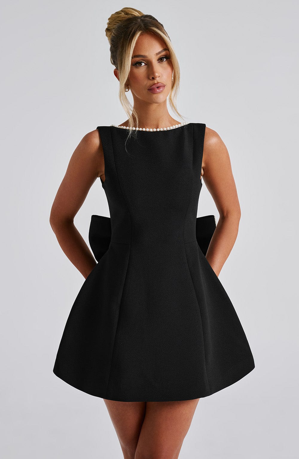 Front close view of black pearl neck mini A-line dress showing sleeveless bodice, seams, and flared skirt
