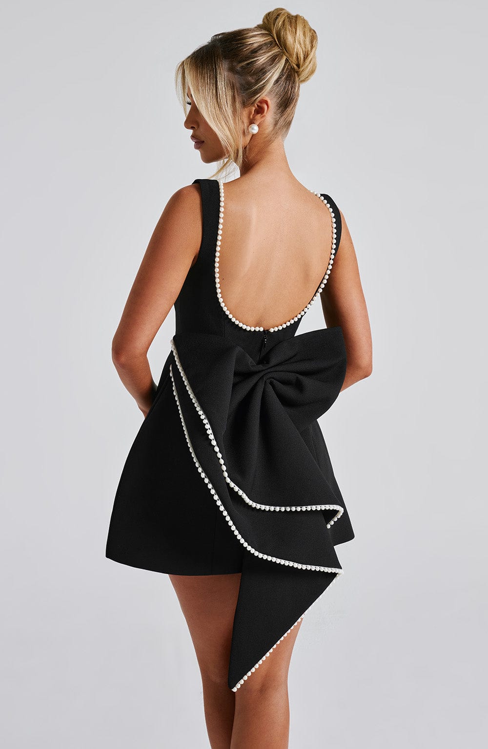 Back view black pearl trim mini A-line wedding guest dress with low scoop back and oversized bow