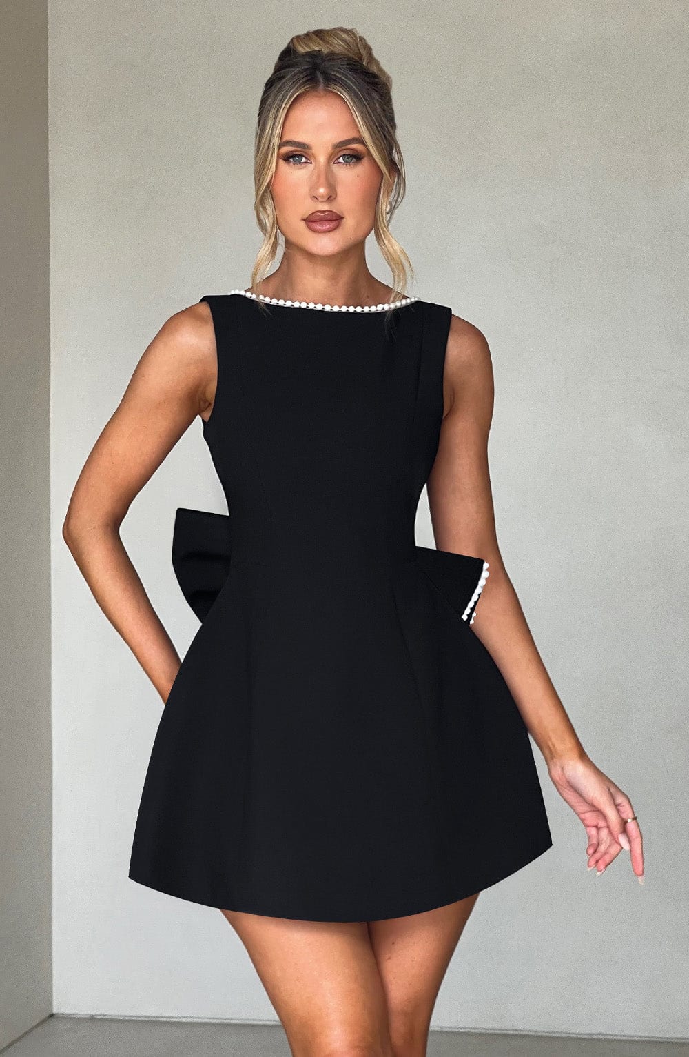 Front view black pearl neck mini A-line wedding guest dress with sleeveless bodice and structured skirt