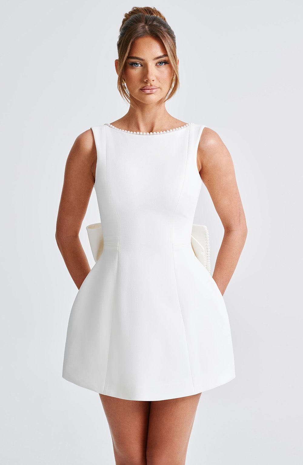 White pearl neckline mini A-line wedding guest dress, front view with structured skirt and bow detail