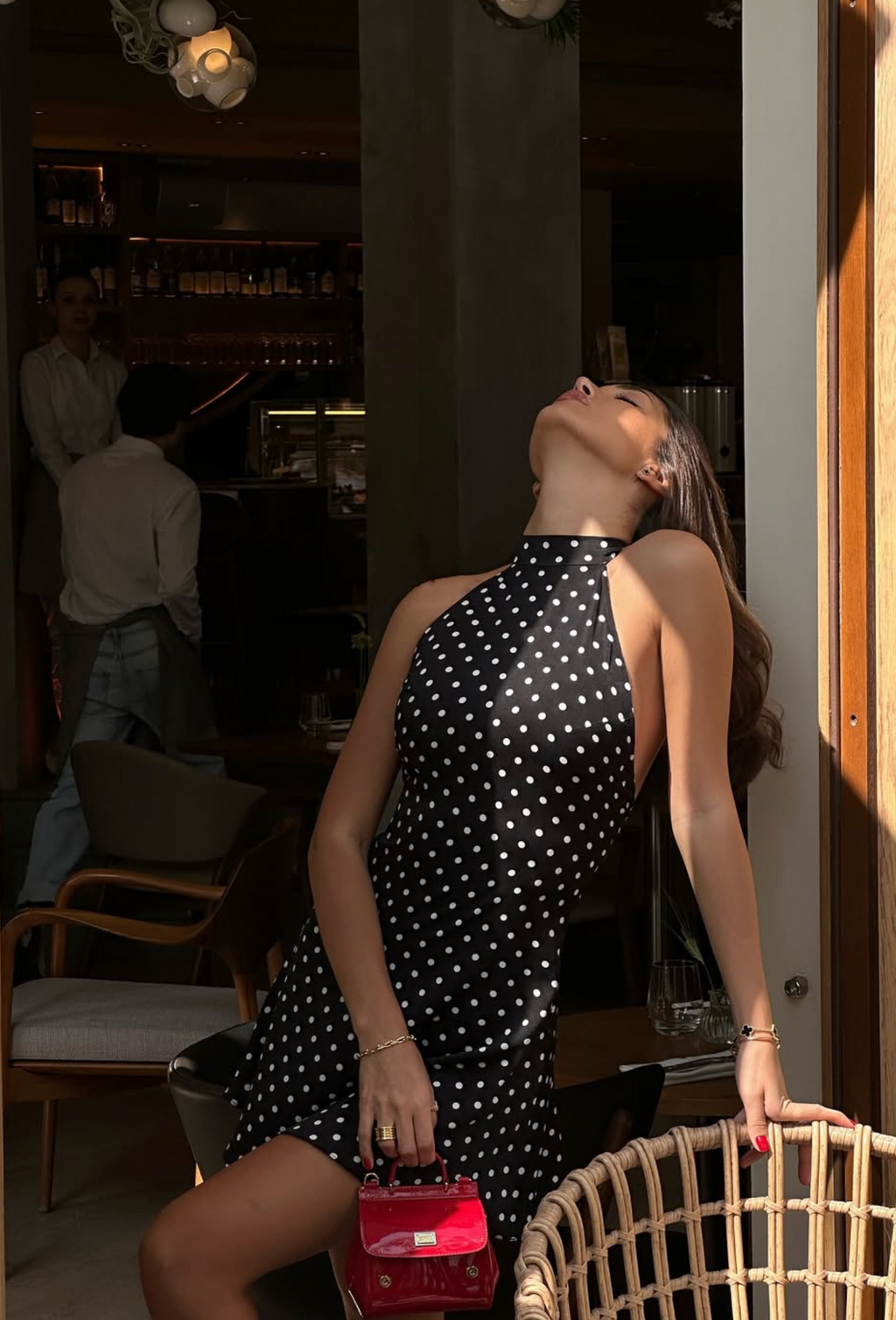 Close-up of black polka dot halter neckline and open side cut, mini dress detail