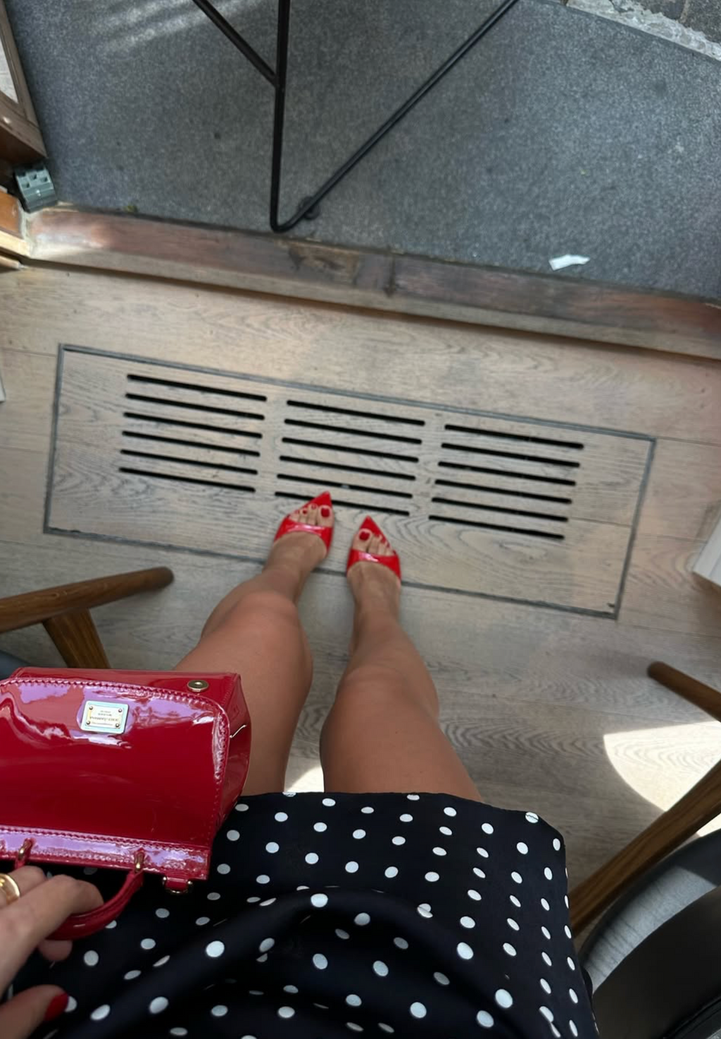 Point-of-view hem of black polka dot mini dress with red pointed heels, wedding shoes
