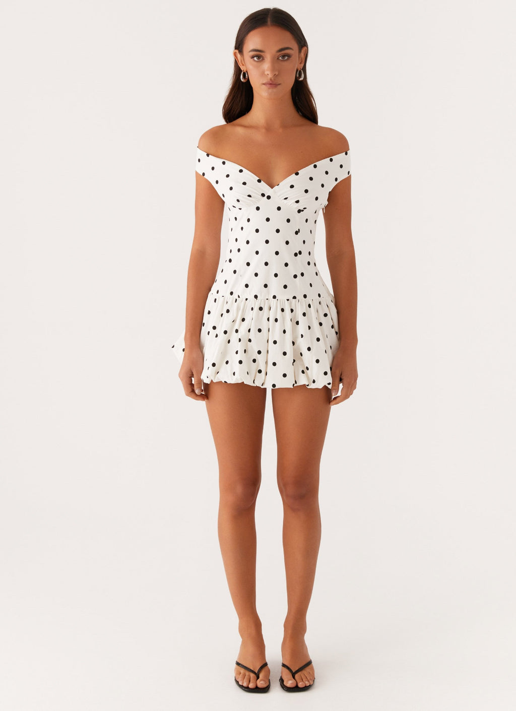 Front full-length view of white polka dot off shoulder mini dress with bubble skirt, wedding guest dress