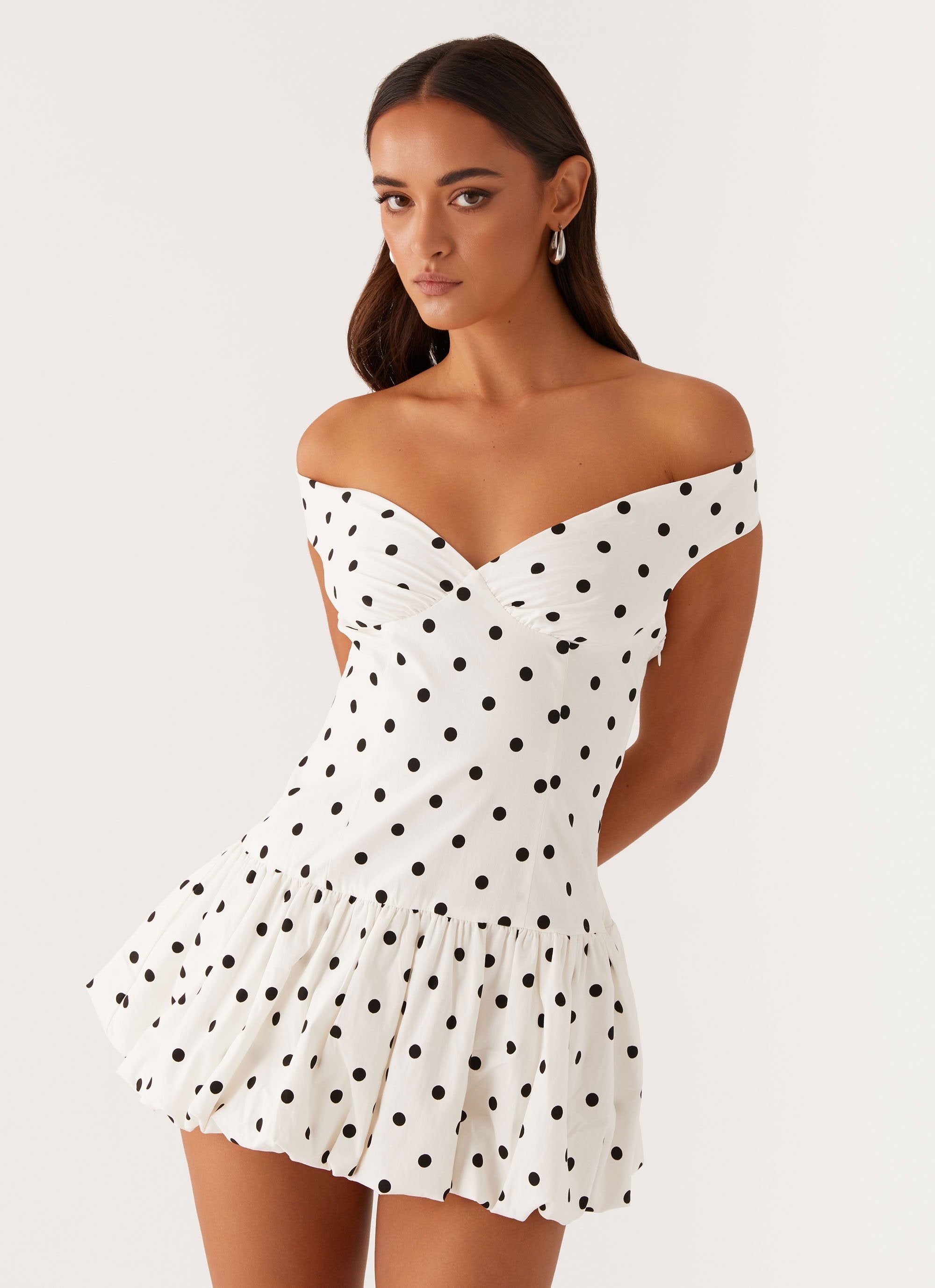 Close-up of white polka dot off shoulder mini dress bodice with sweetheart neckline, wedding guest dress