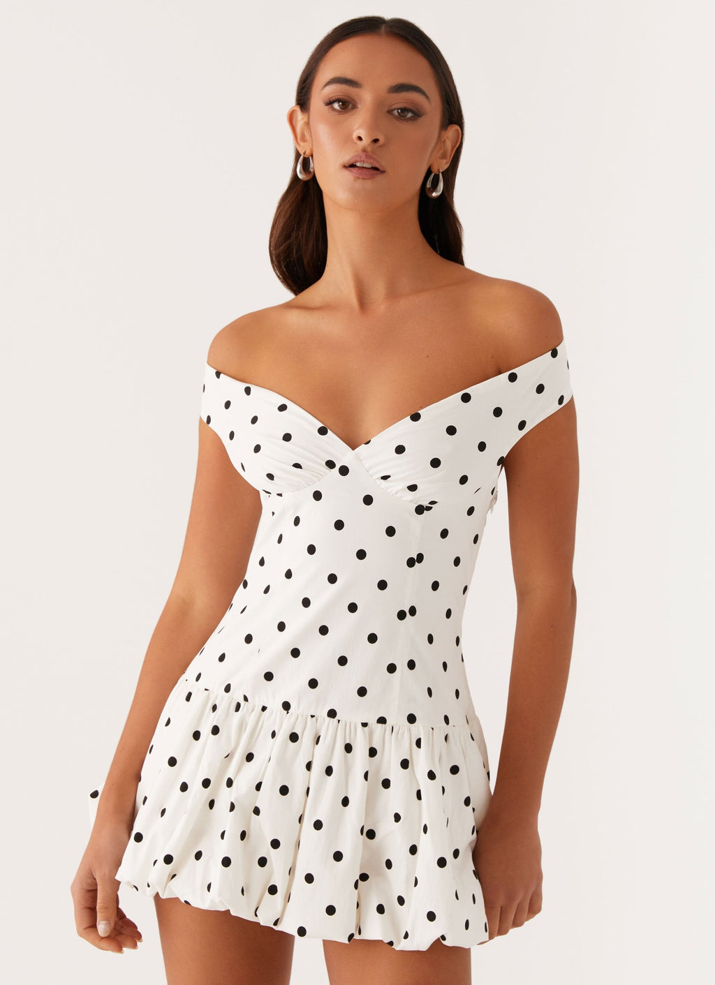 Off shoulder white polka dot mini dress close-up showing ruched bust and fitted waist, wedding guest dress
