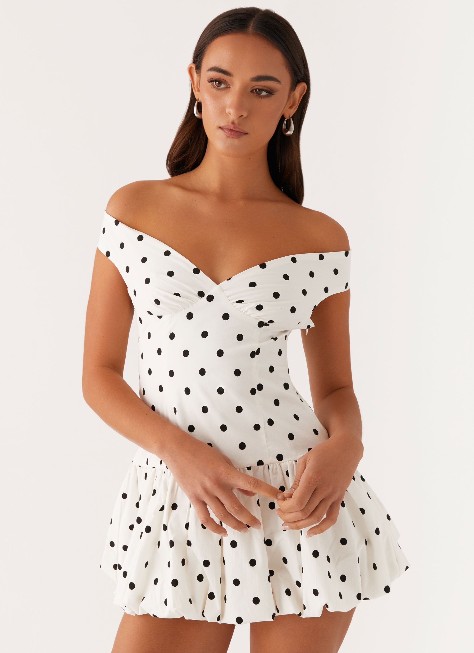 Detail view of white polka dot off shoulder mini dress with wrap-style bust and bubble skirt hem