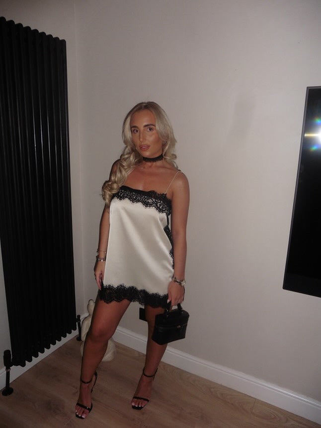 Wedding guest satin lace mini dress in white with black lace trim and a mini handbag