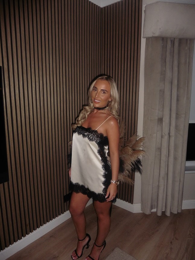 Side view of white satin lace mini dress with black scalloped trim and open-back straps