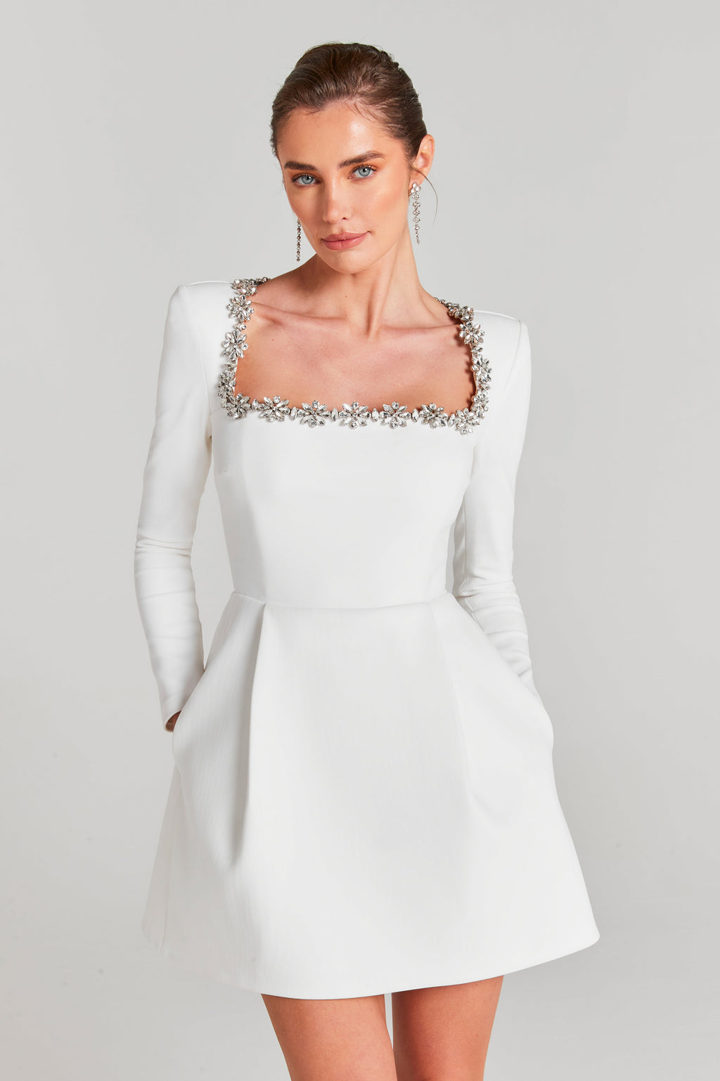 Close-up of white velvet wedding guest dress with jeweled square neckline and fitted sleeves