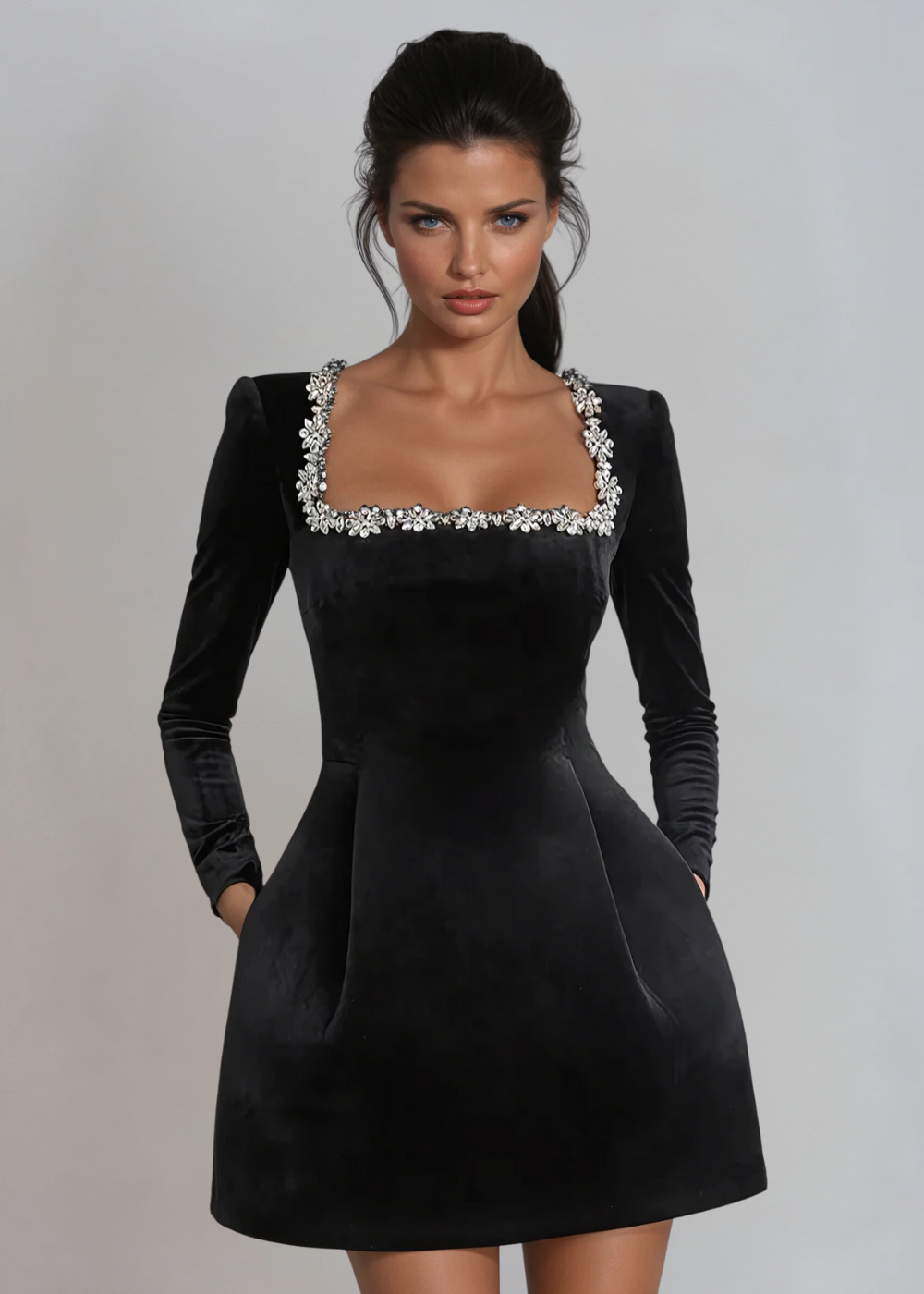 Close-up of black velvet wedding guest dress with jeweled square neckline and long sleeves